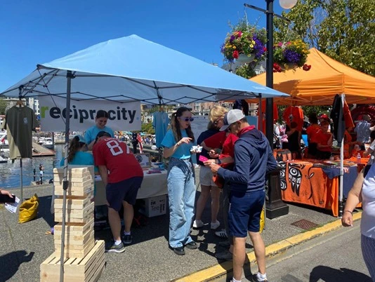The Reciprocity Trusts tent promoting giving back to indigenous communities at a local event.